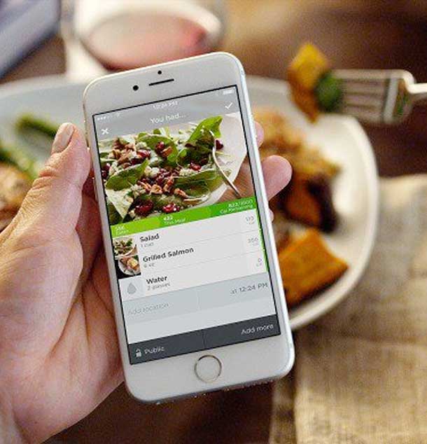 Woman counting calories on a mobile app while eating