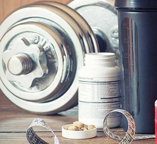 Protein supplement, weight, measuring tape on wood surface