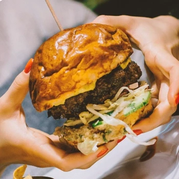 hands holding a large burger