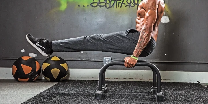 A strong man using paralette bars for calisthenics