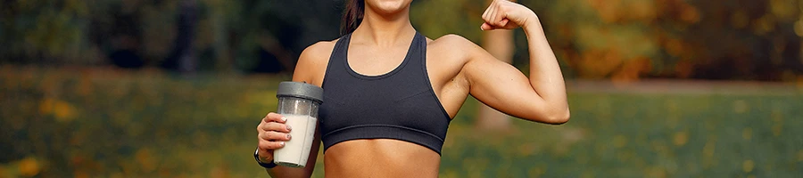 Woman holding supplement drink while flexing muscle