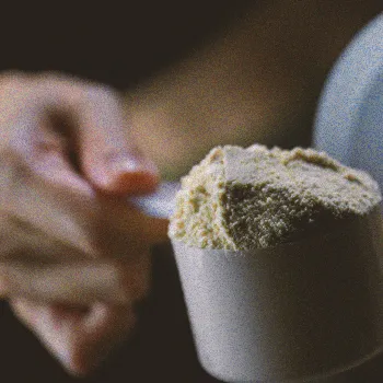 A person holding a scoop of pre-workout powder