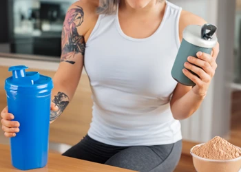 woman drinking whey protein shake in gym