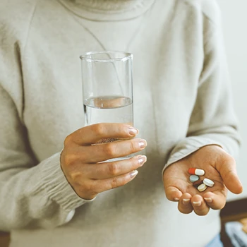 a person holding a glass of water and supplements